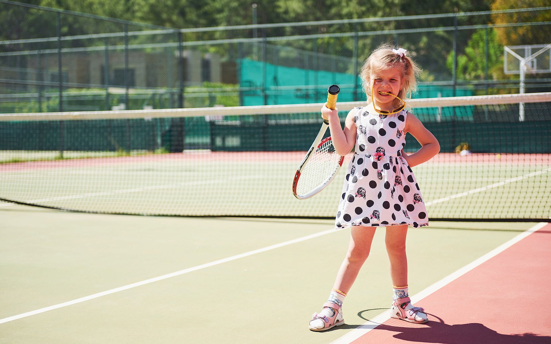 cute little girl playing tennis on the tennis court outside